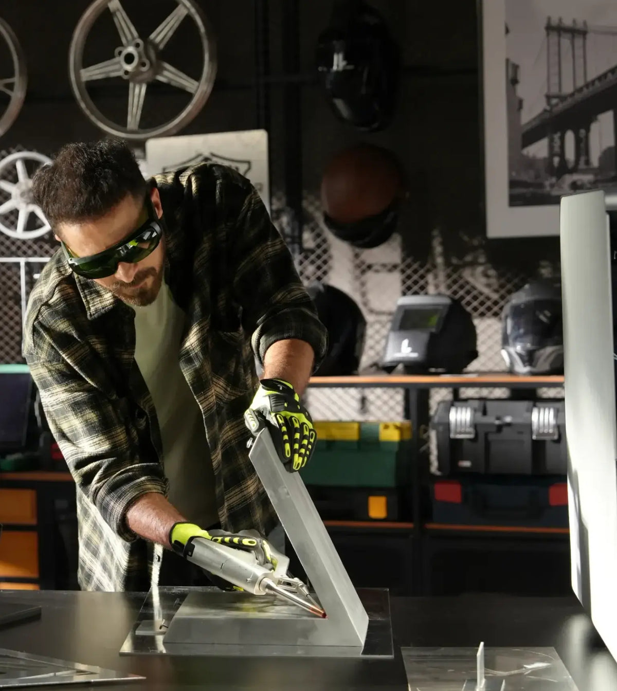 Worker guiding a LaserCyber laser welding tool along a metal frame