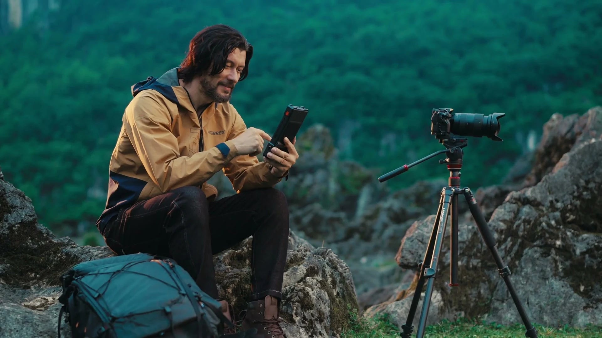 An outdoor creator reviewing PixelMob beside a camera and tripod in the mountains